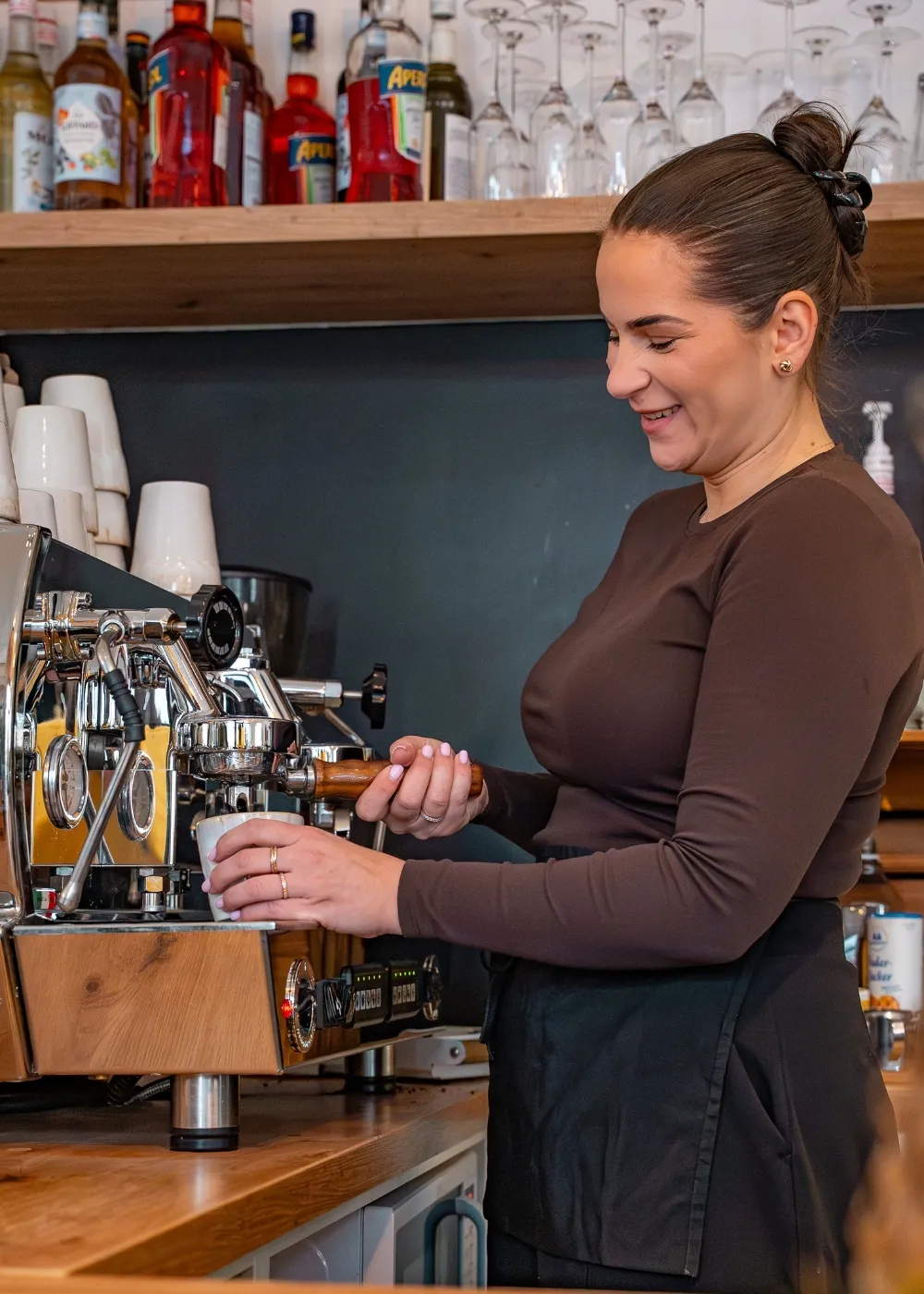 Mitarbeiterin von Sorella bereitet lachend einen Espresso an der Siebträgermaschine zu