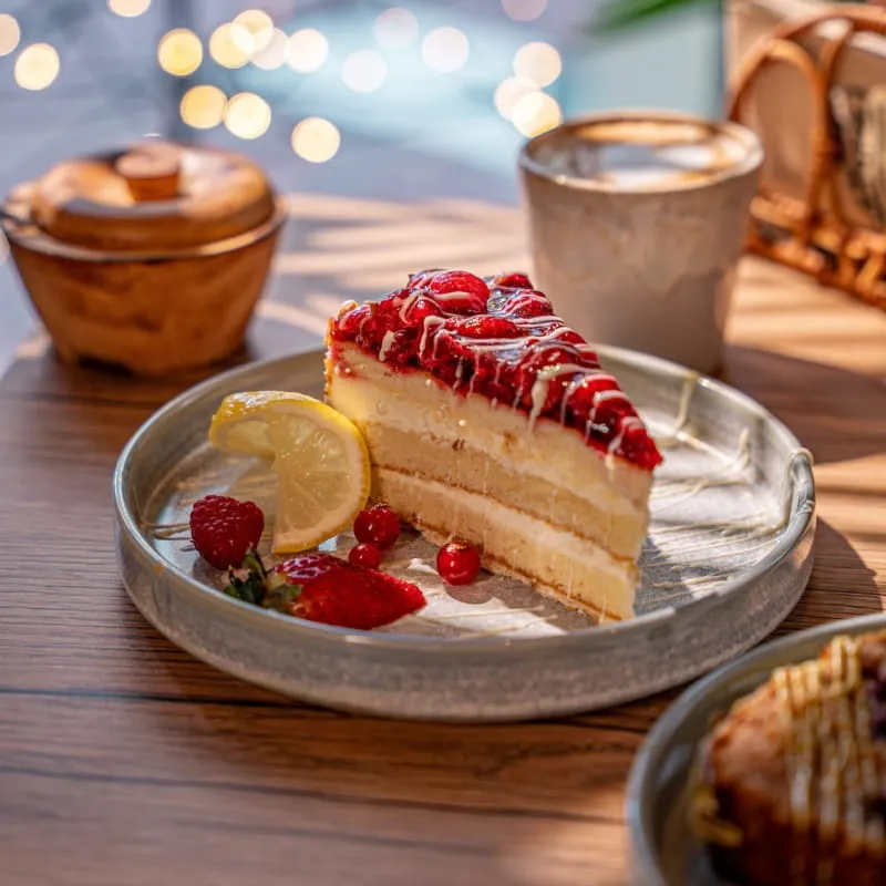 Stück Cheesecake mit Erdbeeren und Blaubeeren auf dunklem Teller