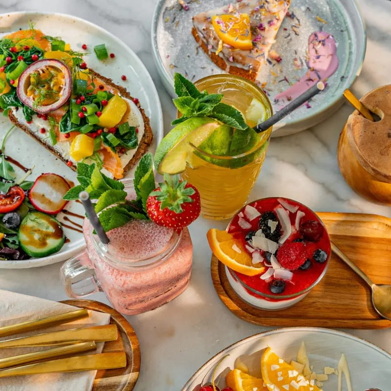 Gedeckter Tisch mit Avocadobrot, Obst und hausgemachten Limonaden