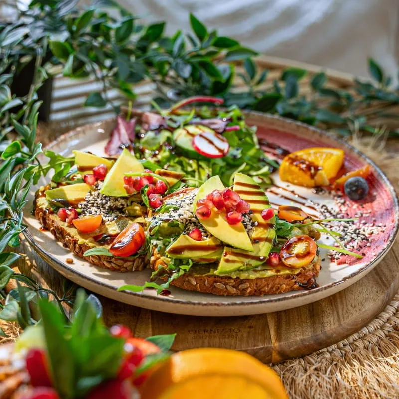 Avocadobrot mit Granatapfel und Sesam auf einer Holzplatte
